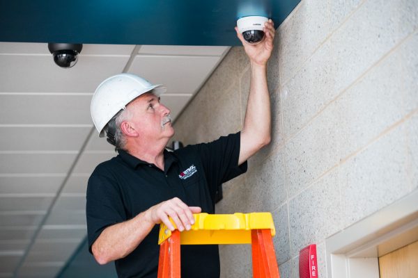 man installing camera on interior of business