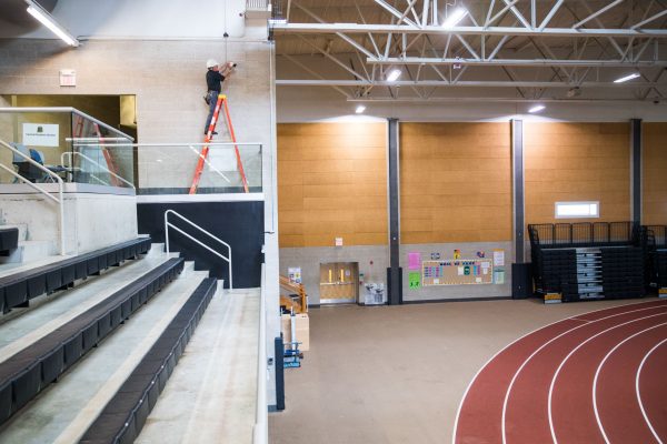 man installing camera surveillance in school gym