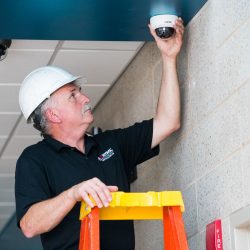 man installing camera on interior of business