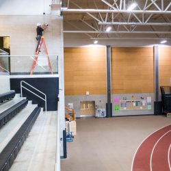 man installing camera surveillance in school gym